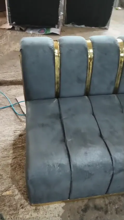 Sofa beludru abu-abu dengan lis emas di sandaran