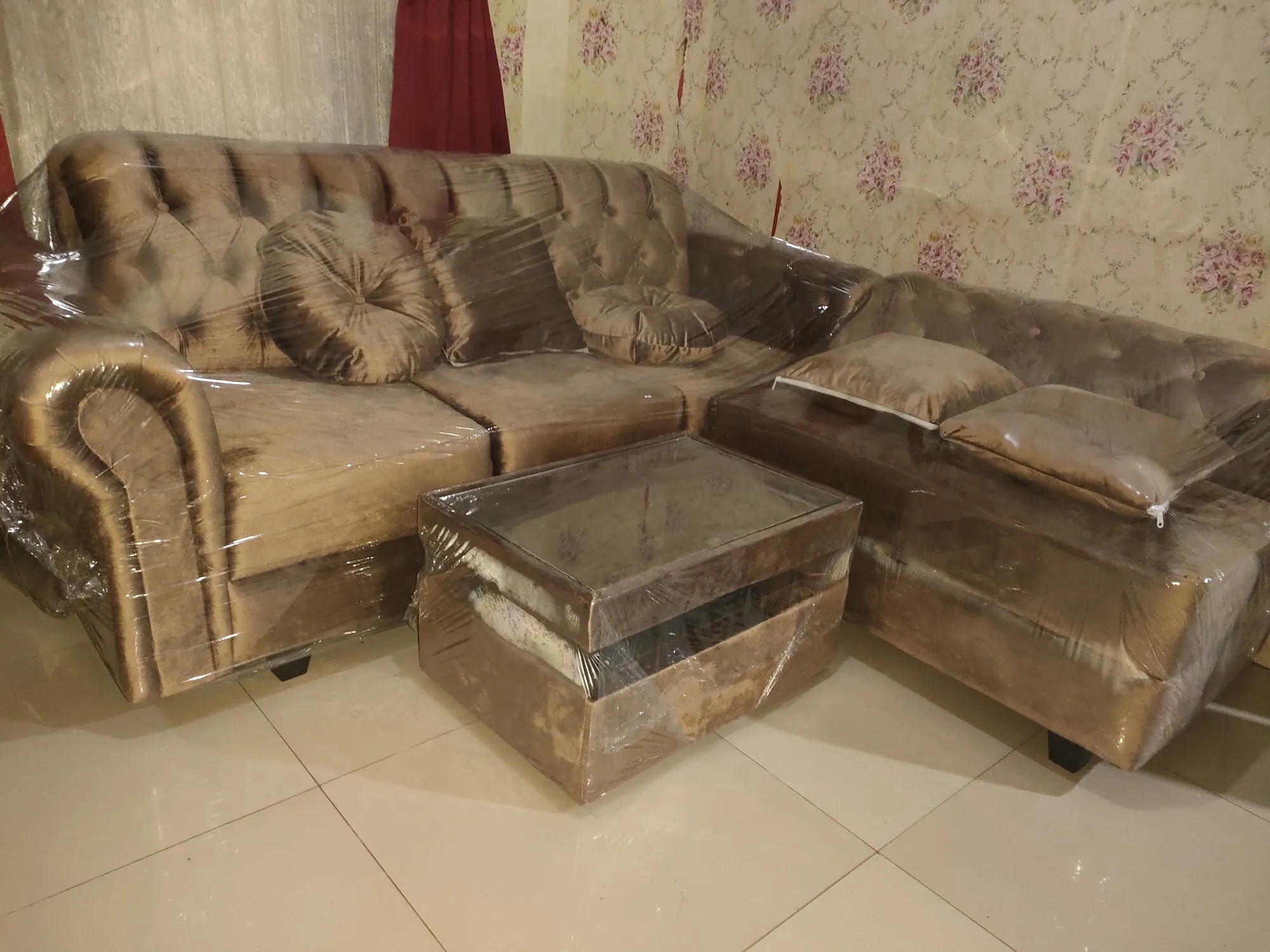 Sofa klasik berkancing warna emas kecokelatan dengan meja kaca di rumah pembeli