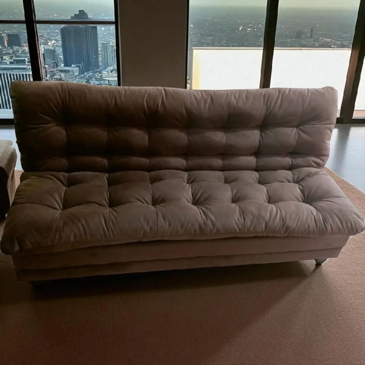 Sofa bed dakron warna cokelat dengan permukaan berkancing